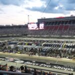 Bristol Motor Speedway at sunset with packed grandstands and NASCAR team haulers on pit road