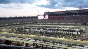 Bristol Motor Speedway at sunset with packed grandstands and NASCAR team haulers on pit road
