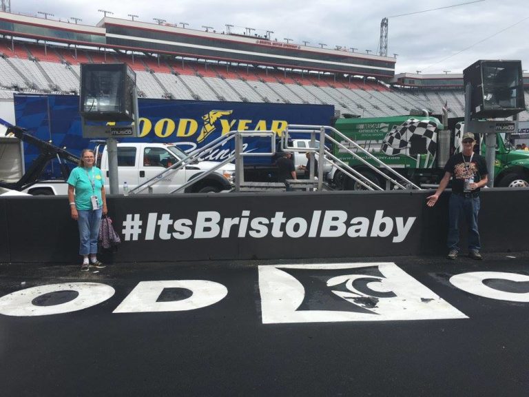 Two NASCAR fans pose at the start/finish line with the #ItsBristolBaby sign at Bristol Motor Speedway.
