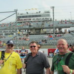 Three race fans pose on the frontstretch at Darlington Raceway before the Southern 500, enjoying their Darlington NASCAR Packages weekend.
