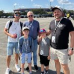 A family enjoying a Bristol NASCAR ticket package with Bristol Motor Speedway visible in the background.