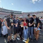 RaceAway Hospitality guests pose outside Bristol Motor Speedway with the grandstands in the background on race day.