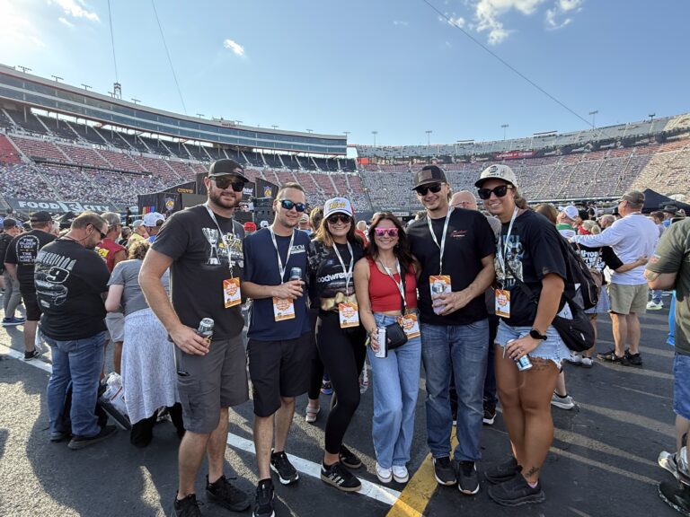 RaceAway Hospitality guests pose outside Bristol Motor Speedway with the grandstands in the background on race day.