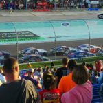 Fans watching cars race at Homestead-Miami Speedway during Homestead NASCAR Packages weekend