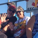 Smiling fans wave from the Darlington Raceway grandstands during the Southern 500, enjoying the view with their Darlington NASCAR Packages experience.