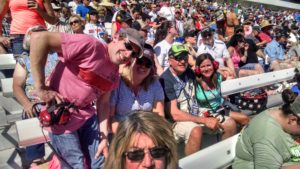 Group of guests enjoying Las Vegas NASCAR Packages in the grandstands at Las Vegas Motor Speedway under bright sunny skies.