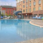 Outdoor pool with waterslide at Hilton Garden Inn Pigeon Forge surrounded by lounge chairs and umbrellas