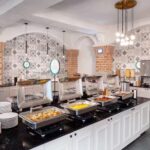 Breakfast buffet at Embassy Suites Orlando – North featuring hot and cold selections in a bright, stylish dining area included with RaceAway Daytona tour packages.