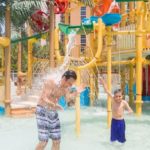Father and son playing under water features at the Embassy Suites Myrtle Beach resort kids’ splash park.