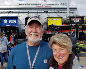 Smiling couple on pit road at Martinsville Speedway with grandstands in the background