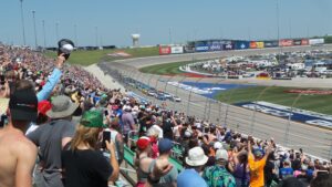 RaceAway Kansas NASCAR Package guests watch as NASCAR cars race around Kansas Speedway’s wide, high-banked turns.