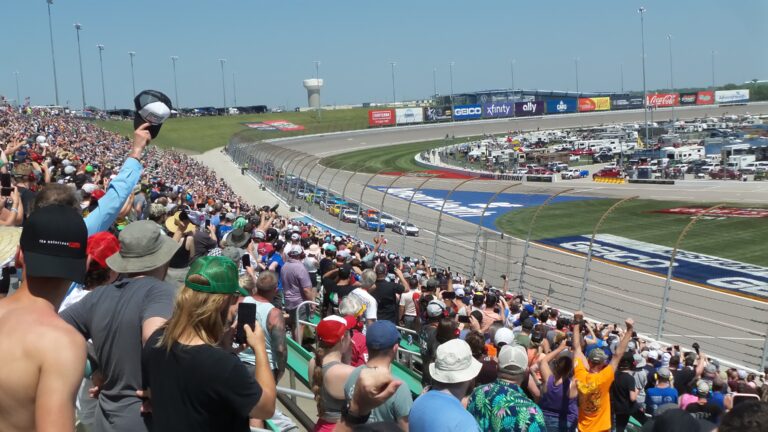 RaceAway Kansas NASCAR Package guests watch as NASCAR cars race around Kansas Speedway’s wide, high-banked turns.