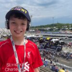 Young fan smiling in the grandstands overlooking pit road and short-track racing at Martinsville Speedway with Martinsville NASCAR Packages