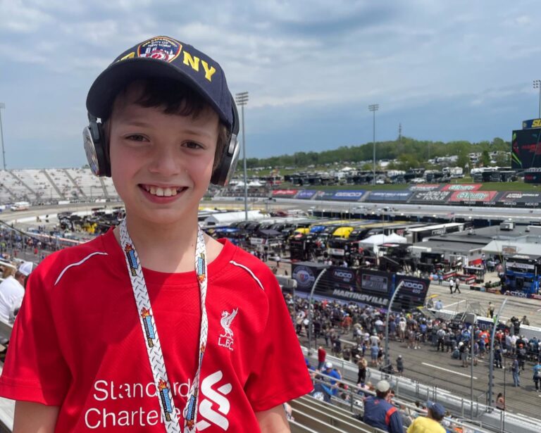 Young fan smiling in the grandstands overlooking pit road and short-track racing at Martinsville Speedway with Martinsville NASCAR Packages
