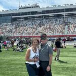 Couple standing on the infield grass at Charlotte Motor Speedway during the May NASCAR weekend.