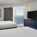 Included with our Darlington NASCAR Ticket Packages: Ocean-view hotel room with two queen beds, flat-screen TV, and private balcony at a Myrtle Beach resort.