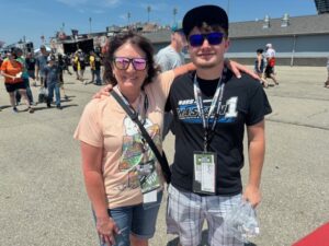 Guests smiling at Iowa Speedway while wearing NASCAR shirts and VIP passes during a RaceAway Hospitality experience.