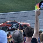 RaceAway guests with Kansas NASCAR ticket packages cheer as the No. 1 car speeds past the grandstands at Kansas Speedway