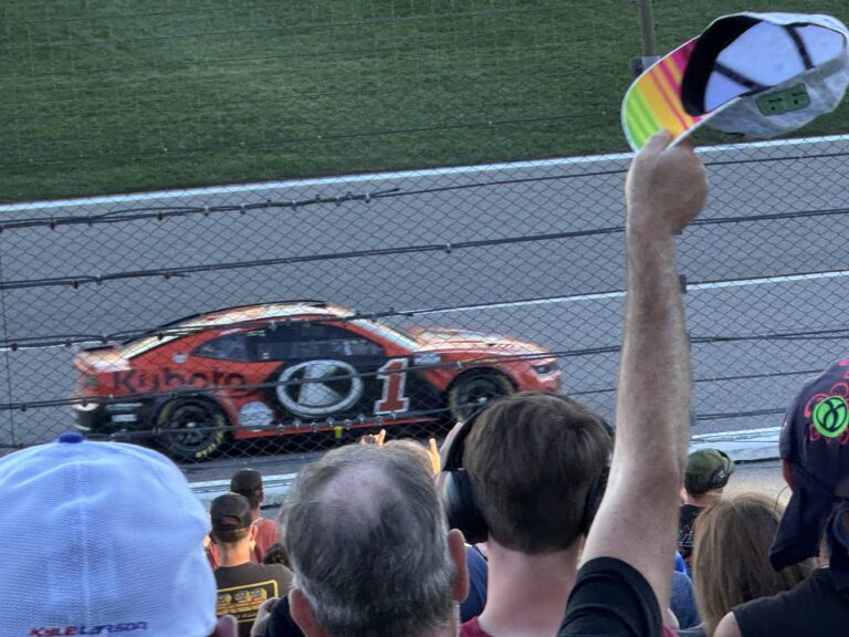 RaceAway guests with Kansas NASCAR ticket packages cheer as the No. 1 car speeds past the grandstands at Kansas Speedway
