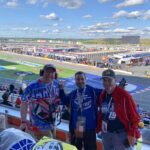 Three race fans enjoying the view from the grandstands at Charlotte Motor Speedway