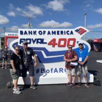 RaceAway Charlotte NASCAR Ticket Package guests posing in front of the Bank of America ROVAL 400 sign at Charlotte Motor Speedway