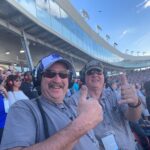 Two RaceAway guests enjoying their Phoenix NASCAR Ticket Package, and giving thumbs up in the grandstands at Phoenix Raceway.