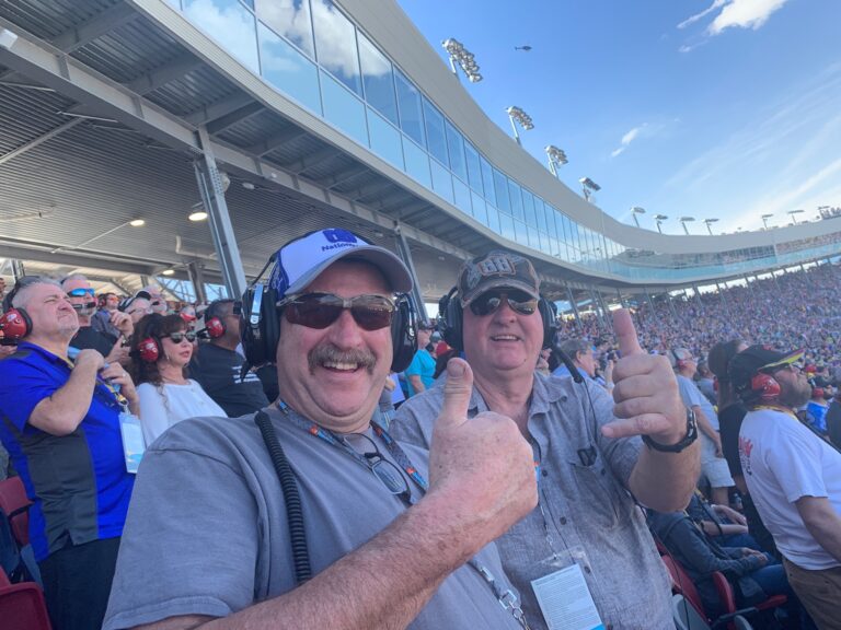 Two enthusiastic fans giving thumbs up in the grandstands at Phoenix Raceway.