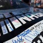 Close-up of autographs from NASCAR fans on a race car at Kansas Speedway, with the RaceAway Hospitality name visible