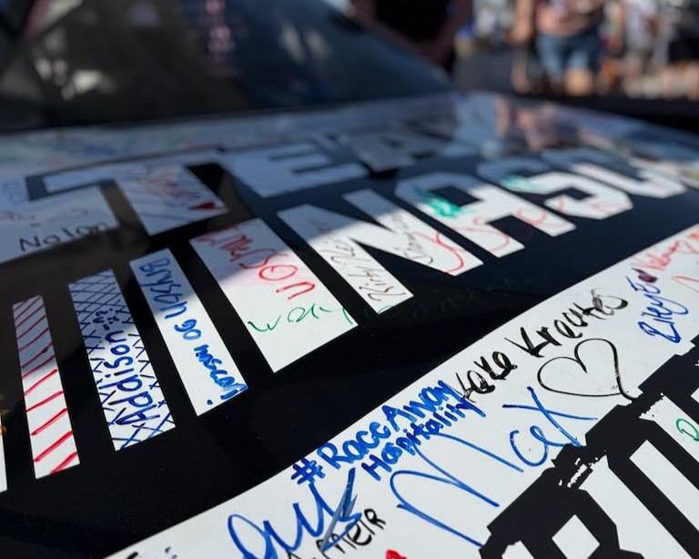 Close-up of autographs from NASCAR fans on a race car at Kansas Speedway, with the RaceAway Hospitality name visible