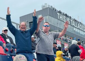 Excited Talladega NASCAR package fans cheering in the grandstands at Talladega Superspeedway.