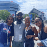 Smiling group of four RaceAway Hospitality guests outside Charlotte Motor Speedway during NASCAR weekend.