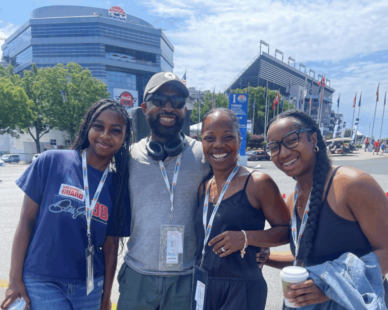 Smiling group of four RaceAway Hospitality guests outside Charlotte Motor Speedway during NASCAR weekend.