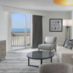 Spacious Myrtle Beach hotel living room with modern furnishings and ocean views, part of Darlington NASCAR Packages.