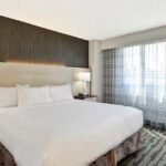 Modern hotel room with king bed, soft lighting, and large window near Charlotte Motor Speedway