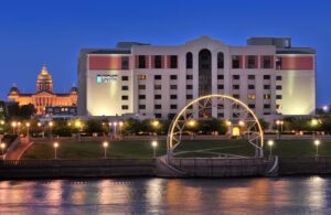 Embassy Suites Des Moines Downtown lit up at night with Iowa State Capitol dome in the background, ideal for Iowa NASCAR Tickets travelers.
