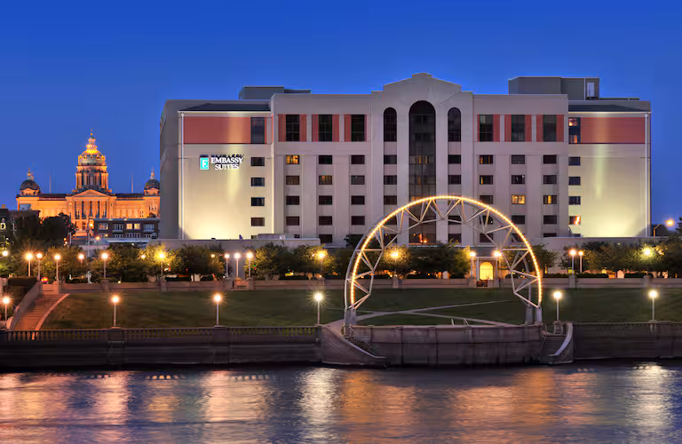 Embassy Suites Des Moines Downtown lit up at night with Iowa State Capitol dome in the background, ideal for Iowa NASCAR Tickets travelers.