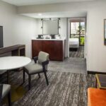 Embassy Suites Orlando North living area with sofa, dining table, and separate bedroom, featured in RaceAway NASCAR tours.