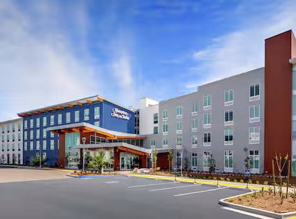 Daytime exterior view of Hampton Inn & Suites San Diego Airport Liberty Station with palm trees and welcoming entrance.