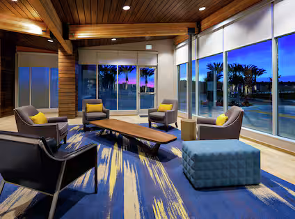 Modern hotel lobby with seating area and reception desk at Hampton Inn & Suites San Diego Airport Liberty Station.