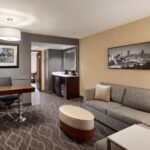Living area of a two-room suite at Embassy Suites Atlanta Airport with sofa, desk, and flat-screen TV