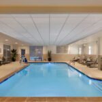 Indoor pool area at Embassy Suites Atlanta Airport with lounge chairs and bright lighting