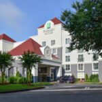Front entrance of Embassy Suites Atlanta Airport hotel with driveway and landscaping
