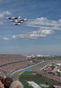 Four jets fly over Daytona International Speedway above packed grandstands during the 2026 Daytona 500 pre-race ceremonies.