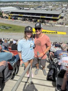 Two RaceAway guests pose in the grandstands at Talladega Superspeedway during a NASCAR weekend.