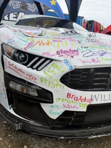 A show car covered in fan signatures is displayed at Talladega Superspeedway during NASCAR weekend.