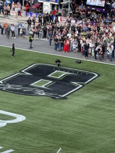 A pre-race ceremony unfolds on the frontstretch grass at Charlotte Motor Speedway during the 2026 Coca-Cola 600, centered around a large No. 43 logo.