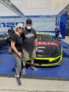 Two RaceAway guests pose beside a display race car at Nashville Superspeedway during the 2026 Cracker Barrel 400 weekend.