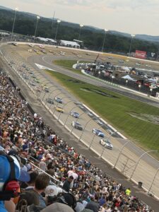 NASCAR Cup Series cars race through the turn at Nashville Superspeedway during the 2026 Cracker Barrel 400 as fans fill the grandstands.