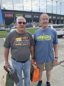 Two RaceAway guests pose outside Kansas Speedway before the 2026 Hollywood Casino 400, one wearing Ryan Blaney gear.