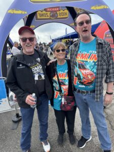 Three RaceAway guests pose in the NASCAR Kids Zone at Kansas Speedway before the 2026 Hollywood Casino 400, with two wearing matching Denny Hamlin shirts.